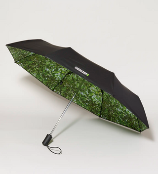 an  side view of an open umbrella with an internal tree canopy design  and the Conservancy logo on the minimal black exterior