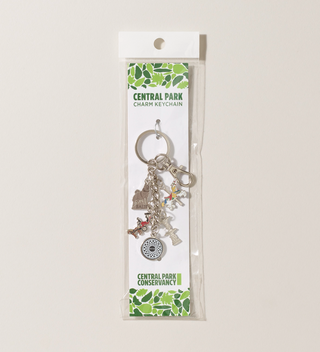 Central Park Conservancy charm keychain in its packaging, featuring several charms including a carousel horse, Imagine mosaic, and Balto