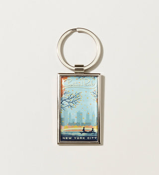 a silver metal keychain with Travel Poster styled artwork of an autumn scene  with  Bow Bridge and   a rowboat in Central Park 