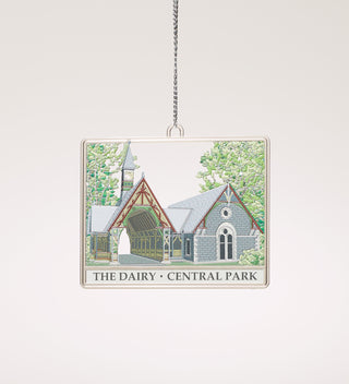 a stamped metal ornament in the design of the Dairy Visitor Center hanging on a thin silver cord  