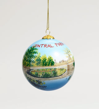 Central Park-themed hanging ornament featuring a bridge over a pond with trees in the background.