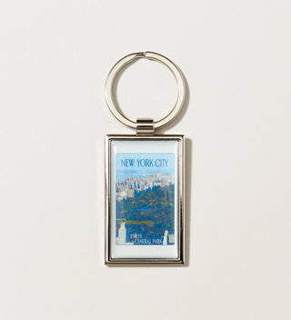 A silver keychain with Travel Poster style artwork of a aerial view of Central Park and the text 'NEW YORK CITY' and 'ENJOY CENTRAL PARK'