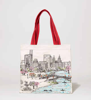 White tote bag with a red handle, featuring an embroidered scene of people rowing boats at Central Park