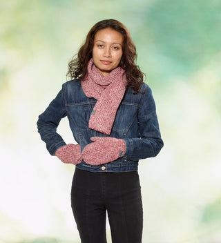 a woman wears a red heather yarn scarf and mittens with custom labels reading 'Central Park Est. 1858' and a denim jacket against a dappled green background