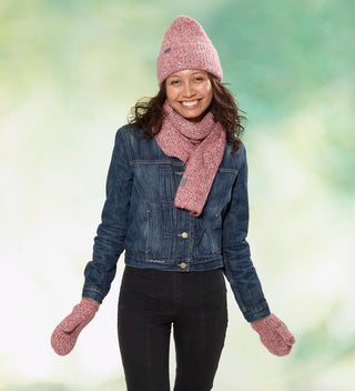 a woman wears a red heather yarn scarf, hat  and mittens with custom labels reading 'Central Park Est. 1858' and a denim jacket against a dappled green background