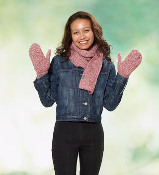 a woman wears a red heather yarn scarf and mittens with custom labels reading 'Central Park Est. 1858' and a denim jacket against a dappled green background