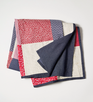 Folded picnic blanket with navy lining and red, white and navy patterned fabric