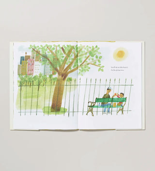 an open book with a watercolor illustration of a  man and child sitting on a bench in a park behind a fence 