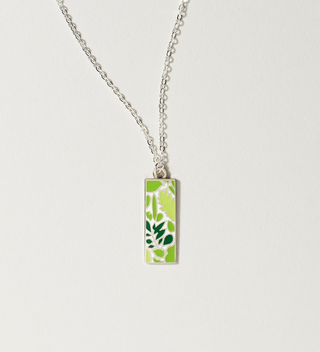 Central Park Conservancy necklace with a green leaf design, displayed on a light grey background