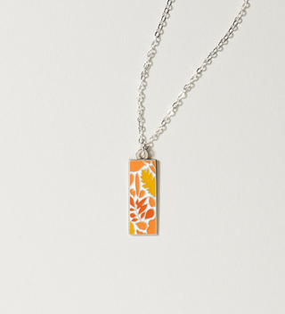 Central Park Conservancy necklace with an orange leaf design, displayed on a light grey background