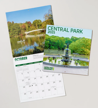 Two calendars, one closed showing the cover photo of Bethesda Fountain and the other open to the month of October featuring an image of Bow Bridge and rowboat 