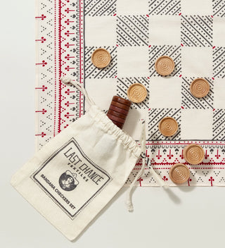 a printed cream, red and grey bandana as a checkerboard with light and dark wooden checkers and  a printed muslin drawstring bag on a  grey background