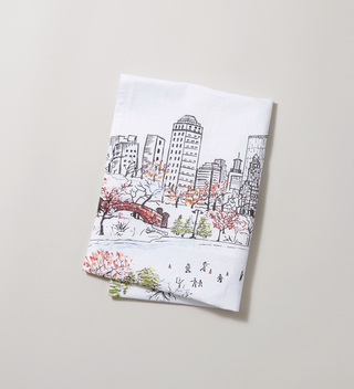 Folded flour sack tea towel featuring a scene of ice skaters at Central Park