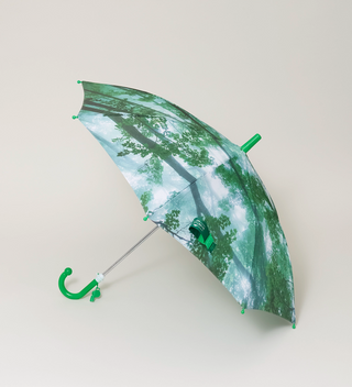 Green-handled umbrella with a design of a forest canopy, partially open, on a light grey background