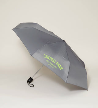 an open grey umbrella with CENTRAL PARK New York City  Since 1858  printed in light green against a light grey background