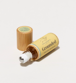 Ava Quinn's "Grounded" essential oil roller lying on its side, with the cap standing up 