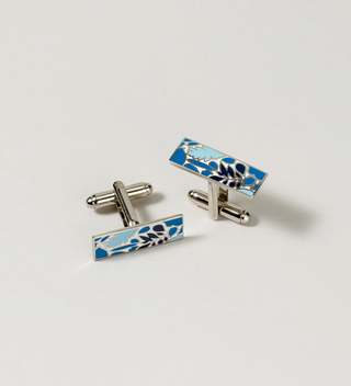 Close-up of Central Park Conservancy cufflinks with a blue and white floral design, on a light grey background