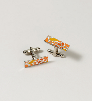 Pair of Central Park Conservancy cufflinks with an orange and white leaf design, displayed on a light grey background