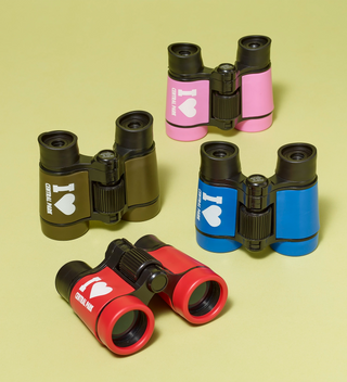 Four pairs of colorful binoculars with 'I heart Central Park' text, displayed on a yellow background. Colors include black, pink, blue, and red.