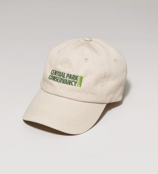 a tan 6-panel hat featuring the Central Park Conservancy logo in green on the front on a grey background