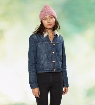 a woman posing in red and white marled yarn knit hat with woven wraparound tag that reads 'Central Park Est. 1858, NYC' in front of a dappled green background