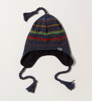 a striped navy knit hat with earflaps, top tassel and tassel ties and a woven wrap-around label with 'Central Park Est. 1858, NYC' on a grey background