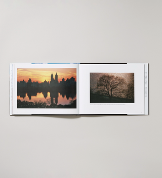 "Windows on Central Park: The Landscape Revealed" book opened to showcase two captioned photographs of trees and a sunset