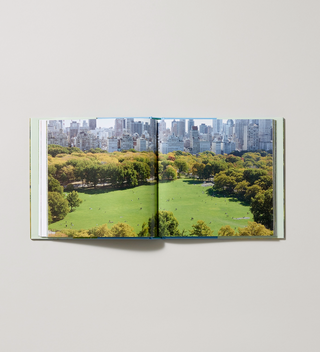 Inside spread of Hardcover book titled "Seeing Central Park: The Official Guide Updated and Expanded" by Sara Cedar Miller with pages displaying an aerial view of Central Park with a city skyline in the background