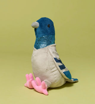 Plush toy shaped like a pigeon with blue and gray colors and pink feet, on a light green background.