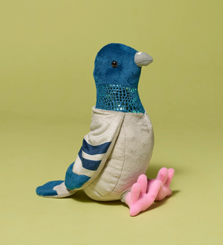 Plush toy shaped like a pigeon with blue and gray colors and pink feet, viewed from a different angle, on a light green background.