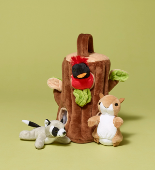 Plush toy shaped like a tree stump with a squirrel and racoon sitting outside of it, on a light green background.