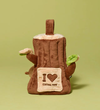 Plush toy shaped like a tree stump with an opening door with   'I Love Central Park' embroidered on it, on a light green background.