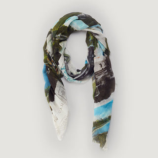 a light scarf printed with a vintage postcard design is rolled into a circle on a grey background