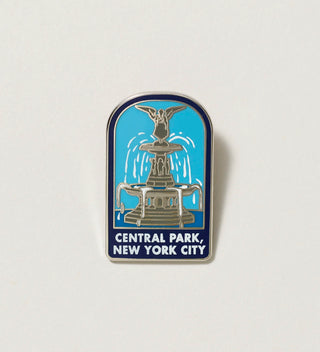 Close-up of a Central Park pin featuring a fountain with 'Central Park, New York City' text on a white background.