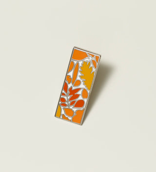 Central Park Conservancy pin with an orange leaf design, displayed on a light grey background