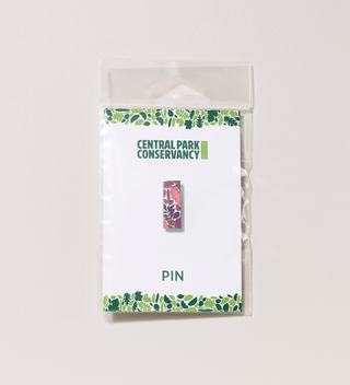 Packaged Central Park Conservancy pin with a  pink and purple leaf design, displayed on a light grey background
