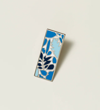 Central Park Conservancy pin with a blue leaf design, displayed on a light grey background