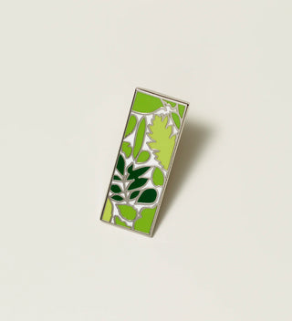 Central Park Conservancy pin with a green leaf design, displayed on a light grey background