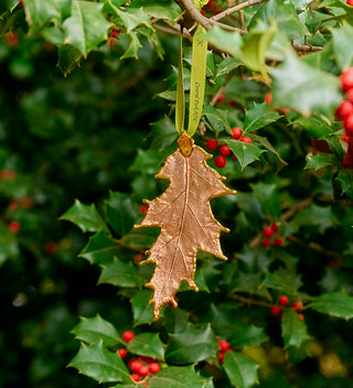 a copper and gold embellished keepsake ornament with a green ribbon reading Central Park NYC hangs on a Holly tree in Central Park 