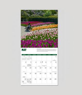 A single-page monthly calendar spread showing a colorful flower garden photograph on the top half and a May calendar grid on the bottom half, centered on a light gray background.