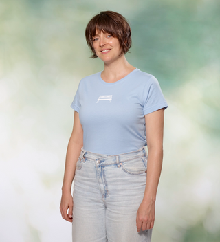 Woman posing while wearing a light blue  t-shirt with a Central Park bench