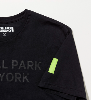 Close-up of the Central Park Conservancy green Park mark on the sleeve of a black "Central Park New York" t-shirt