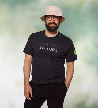 Man posing while wearing a black "Central Park New York" t-shirt and beige "Central Park New York" bucket hat