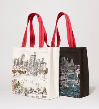 White and black tote bags with red handles featuring embroidered scenes of Central Park