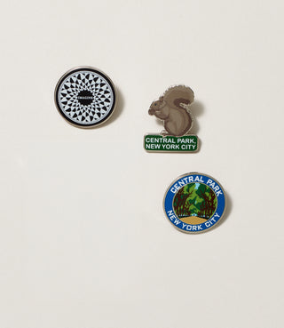 Three pins featuring designs of the Imagine geometric mosaic in Strawberry Fields, a squirrel, and the elm tress on the Mall in Central Park on a light gray background.