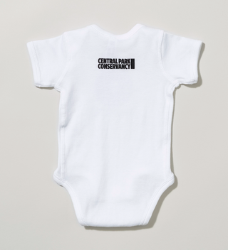 Back view of a white baby onesie with 'Central Park Conservancy' logo near the neckline.