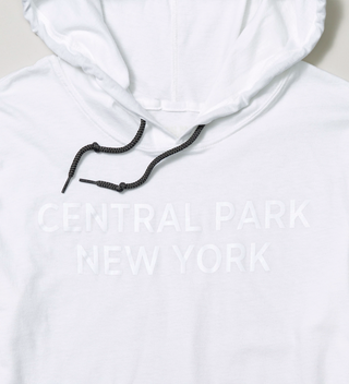 Close-up of "Central Park New York" text in white on a white hoodie with dark gray neck cords 