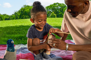 Image of father and son playing at the Great Hill at Central Park, featuring play items sold at the Central Park Conservancy Shop