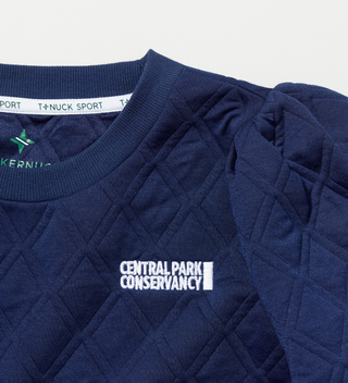 Close-up of the Central Park Conservancy logo on the top of navy quilted shirt