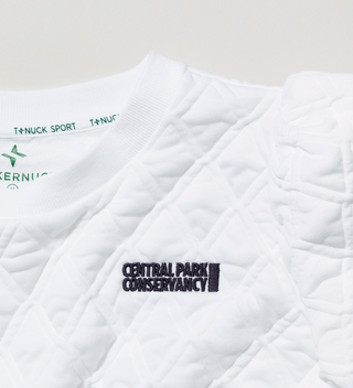 Close-up of the Central Park Conservancy logo on the top of white quilted shirt